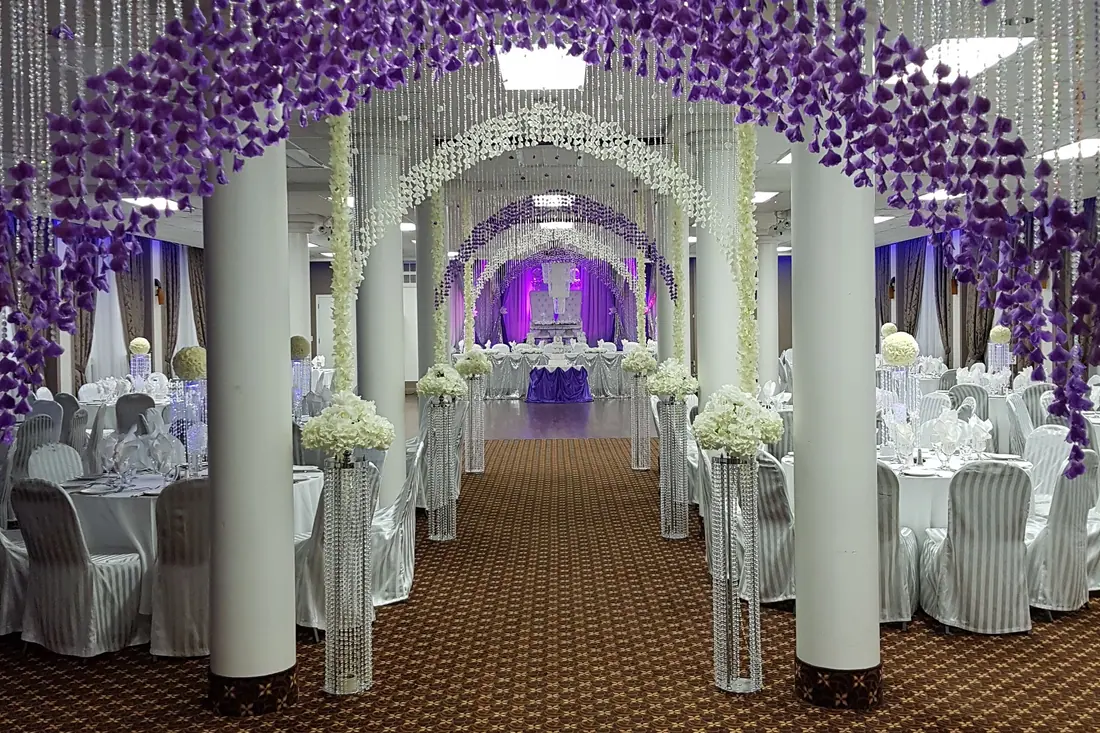 Wedding reception entrance lined with arches of cascading purple wisteria and crystal-beaded columns leading into an Ottawa ballroom